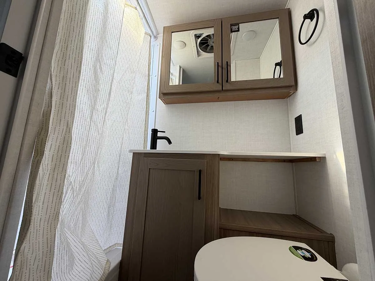 Bathroom in the Rockwood Geo Pro G20SFK with vanity sink, mirrored medicine cabinet, toilet and shower curtain