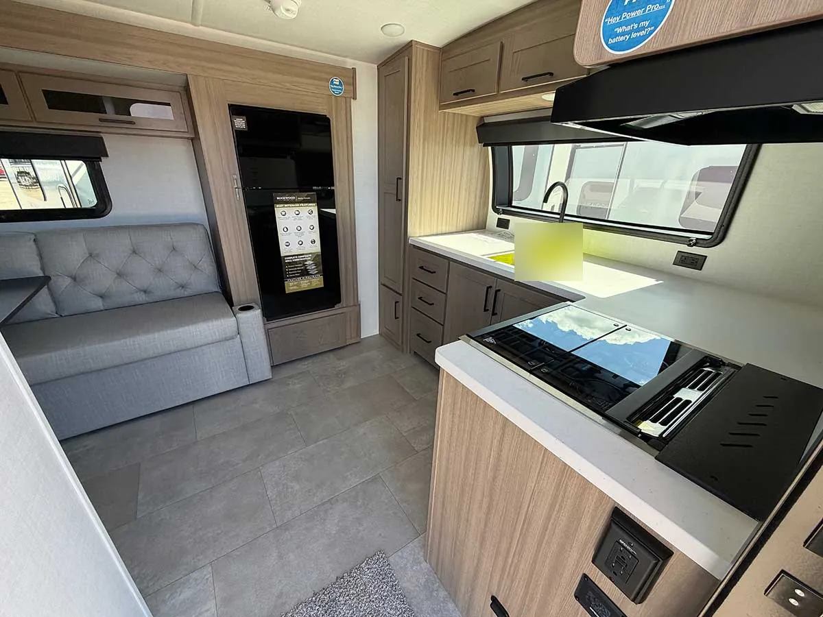 View from the entry door of the G20SFK showing the sofa slide, black glass 12V refrigerator and kitchen counter