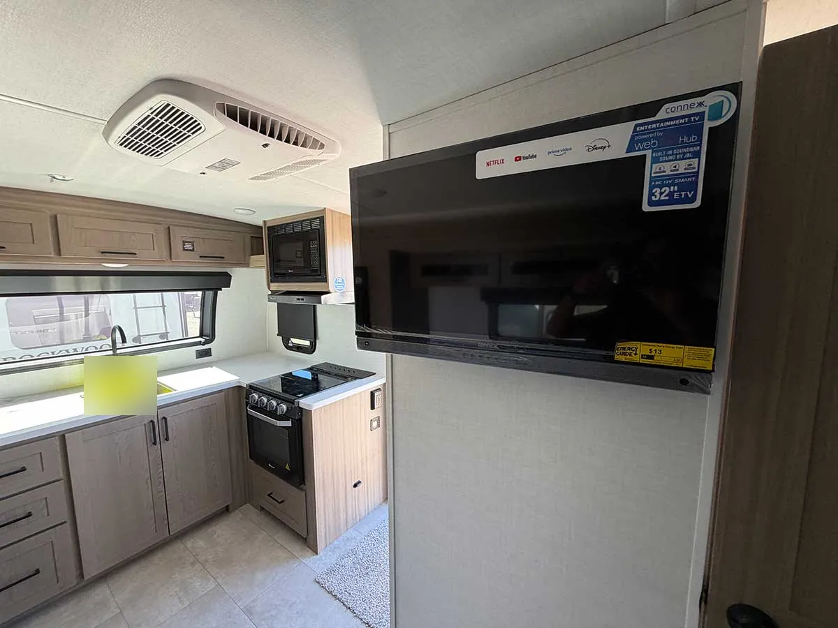 32-inch 12V smart TV on the bathroom wall and the ceiling air conditioner vent near the kitchen in the G20SFK