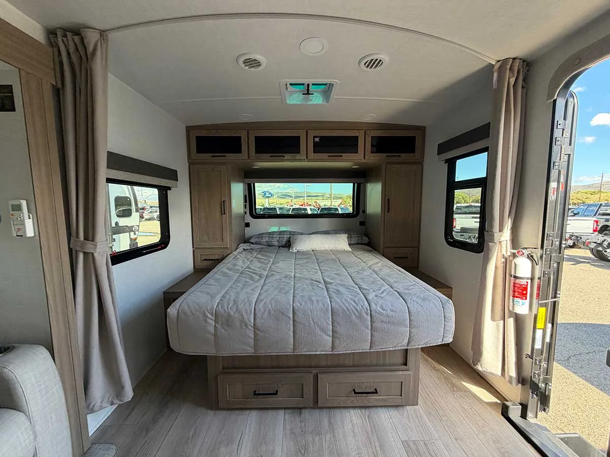 Front walk-around queen bed in the 2213S with under-bed drawers, wardrobes on each side and overhead cabinets