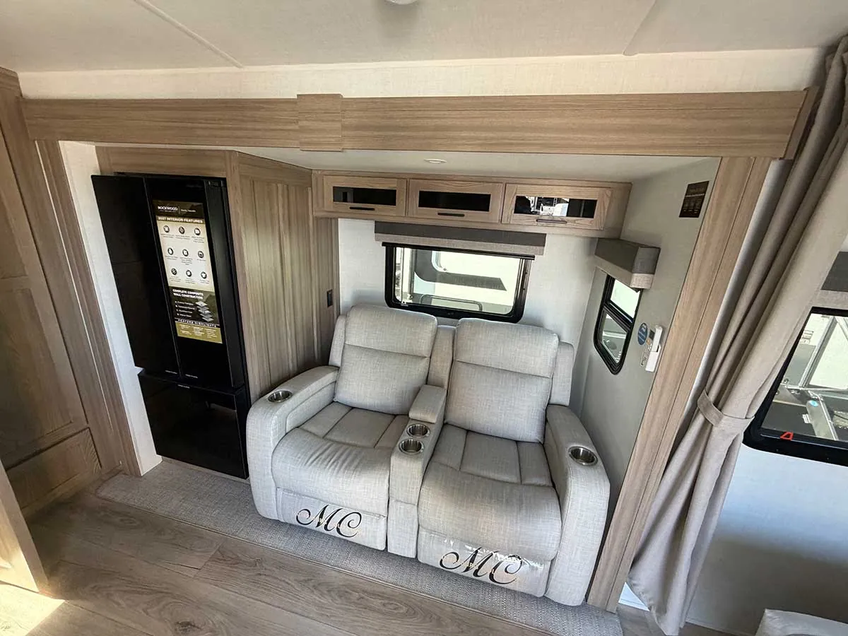 Two theater recliners with cup holders and a tall black 12V refrigerator in the 2213S slide-out
