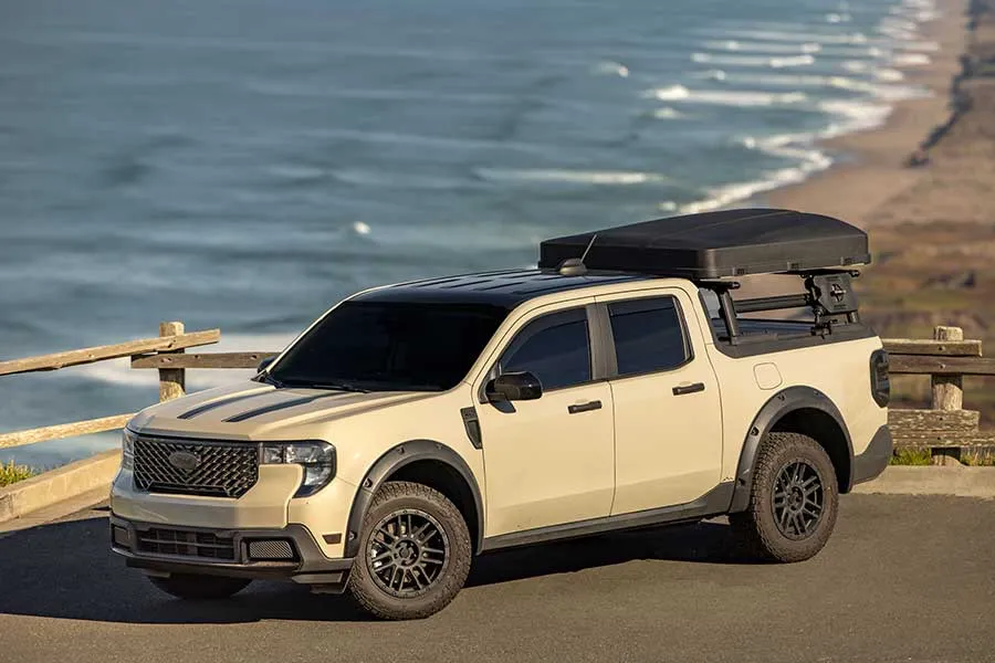 Tan Ford Maverick with a rooftop tent above the ocean